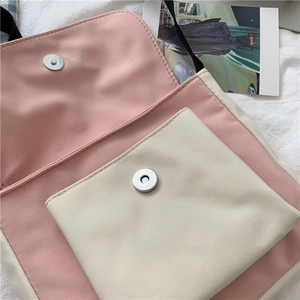 Detail of pink and beige canvas bag showing magnetic snap closure and front pocket