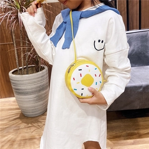 Close-up of a cute yellow donut crossbody bag worn by a girl in a cozy indoor setting