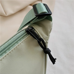 Detail of light green nylon bag showing black zipper and knotted cord puller