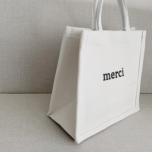 Minimalist white canvas tote bag with black merci print and spacious trapezoid design