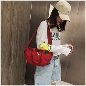 Détail du sac bandoulière en toile rouge avec visage de dessin animé et feuille
