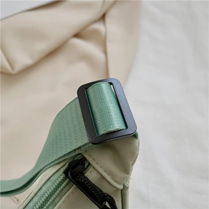 Detail of light green nylon bag showing woven strap and black adjustable buckle