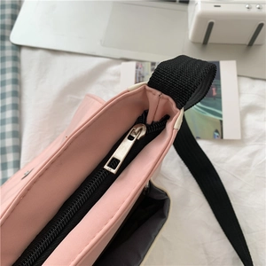 Top detail of pink canvas bag showing black metal zipper closure and fabric shoulder strap