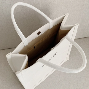 White canvas tote bag with merci print, interior zipper pocket and magnetic closure