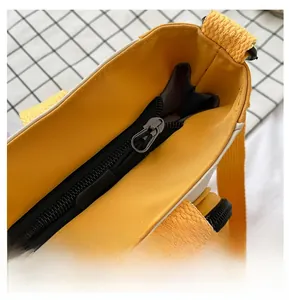 Detailed macro shot of a smooth black zipper with a silver pull on a yellow oxford bag