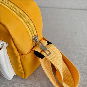 Detail of silver metal zipper and durable nylon fabric on yellow crossbody bag