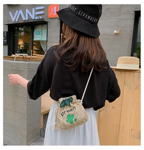 Detail of straw bucket bag with cactus embroidery and drawstring rope strap in street view