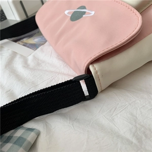 Detail of pink canvas crossbody bag with white star embroidery and black nylon strap