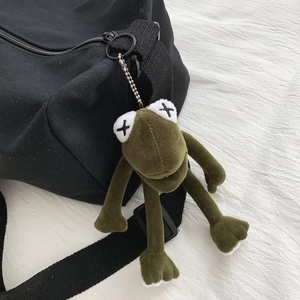 Ciondolo a rana in peluche verde con occhi a croce su una borsa di tela nera