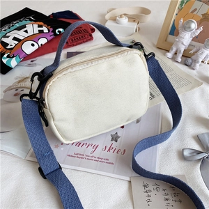 Detail of canvas crossbody bag showing blue strap and white fabric texture