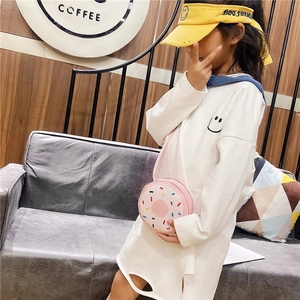 Close-up of a pink donut crossbody bag with colorful sprinkles on a girl outfit
