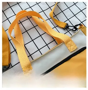 Detail of adjustable woven shoulder strap and metal hook on yellow oxford fabric bag
