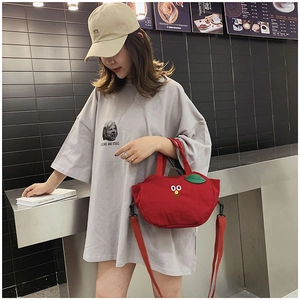 Détail du sac en toile rouge en forme de pomme avec yeux et bandoulière amovible