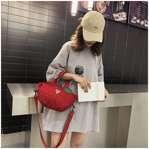 Détail du sac en toile rouge en forme de pomme avec broderie et détail de feuille verte
