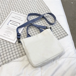 Close-up of off-white canvas tote bag with blue handles and detachable shoulder strap