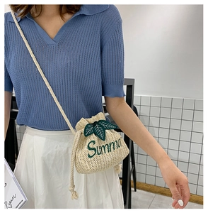 Detail of beige straw bucket bag with green Summer embroidery and leaf accents