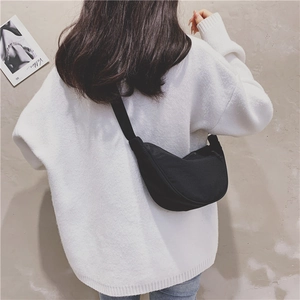 Rear view of model wearing a black nylon crescent crossbody bag with adjustable strap