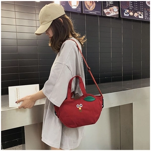 Détail d'un sac bandoulière en toile rouge en forme de pomme avec décor de feuilles