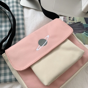 Pink and white canvas crossbody bag with planet embroidery shown in a lifestyle layout