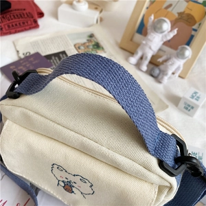 Detail of canvas shoulder bag with cute polar bear embroidery and blue strap handles