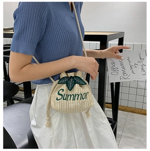 Detail of handmade straw bucket bag with green Summer embroidery and drawstring