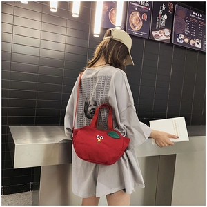 Détail du sac en toile rouge avec broderie cartoon et breloque feuille verte au café