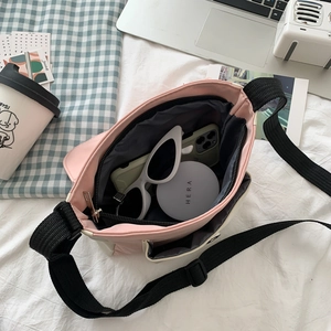 Pink and beige canvas crossbody bag showing daily essentials with adjustable strap