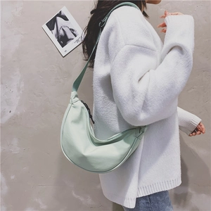 Close-up of mint green nylon crescent bag worn by model in minimalist urban style