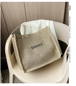 Detailed view of merci linen tote bag with sturdy handles on a cozy indoor chair