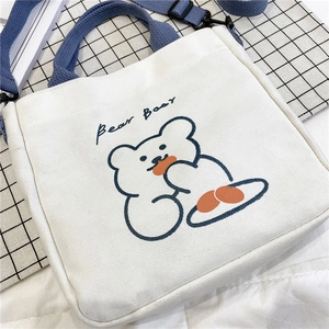 Detail of white canvas tote bag with cute bear print and blue adjustable shoulder strap