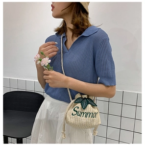 Detail of straw bucket bag with Summer embroidery and green leaf accents
