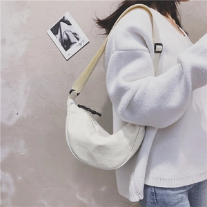 Model wearing white nylon crescent bag with adjustable strap on grey wall background