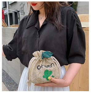 Detail of woven straw bucket bag with cactus embroidery and drawstring closure