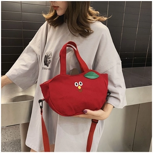 Détail du sac en toile rouge en forme de pomme avec broderie et bandoulière réglable