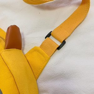Yellow canvas duck crossbody bag featuring adjustable strap and leather accent details
