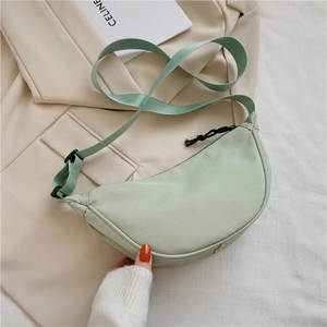 Detail of light green nylon crescent bag with adjustable strap on a beige suit
