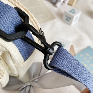Close-up of durable canvas strap connection with black matte hook and D-ring buckle