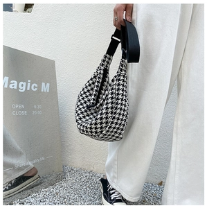 Close-up of black and white houndstooth half-moon bag with adjustable wide canvas strap
