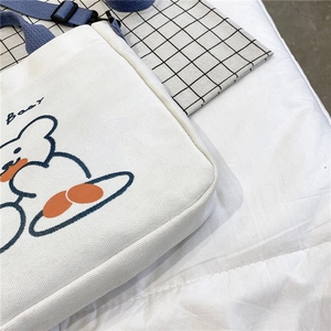 Detail shot of cute bear print and orange text on off-white canvas tote bag