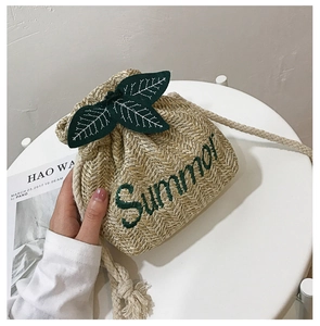 Detail of beige straw bucket bag with green Summer embroidery and leaf accents