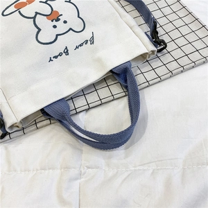 Detail of cute bear print on white canvas tote with contrast blue handles and shoulder strap