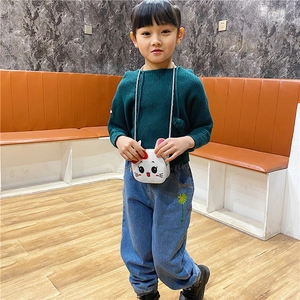 Detail of child wearing white cartoon rabbit crossbody bag with red bow decoration