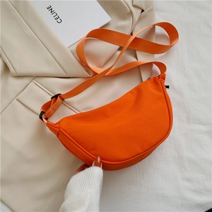 Detail of an orange nylon crescent crossbody bag featuring an adjustable wide strap