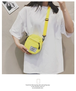 Detail of yellow canvas mini crossbody bag featuring woven brand tag and metal hardware