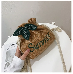 Detailed macro view of woven straw bucket bag with green Summer embroidery and cotton ropes