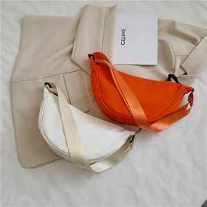 Flat lay of nylon crescent shoulder bags in orange and off-white with wide woven straps