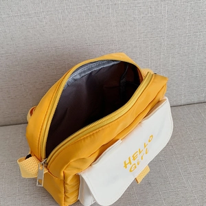 Yellow canvas crossbody bag with HELLO Girl print shown from a top-down interior angle