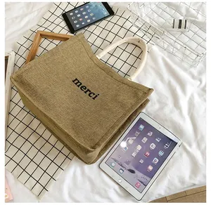 Large jute tote bag with merci print and thick cotton rope handles shown next to an iPad