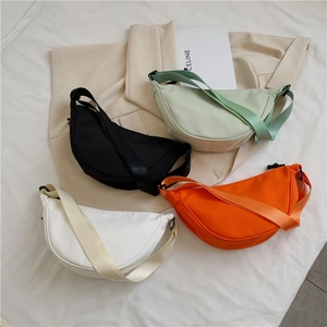 Flat lay of nylon crescent bags in black, green, orange and white with adjustable straps
