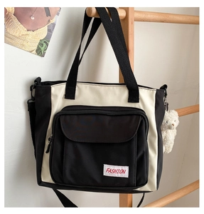 Detail of contrast oxford tote bag featuring front zipper pocket and plush bear charm